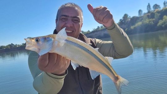 Paisaje del lago Los Molinos en Córdoba, con un pescador en actividad.