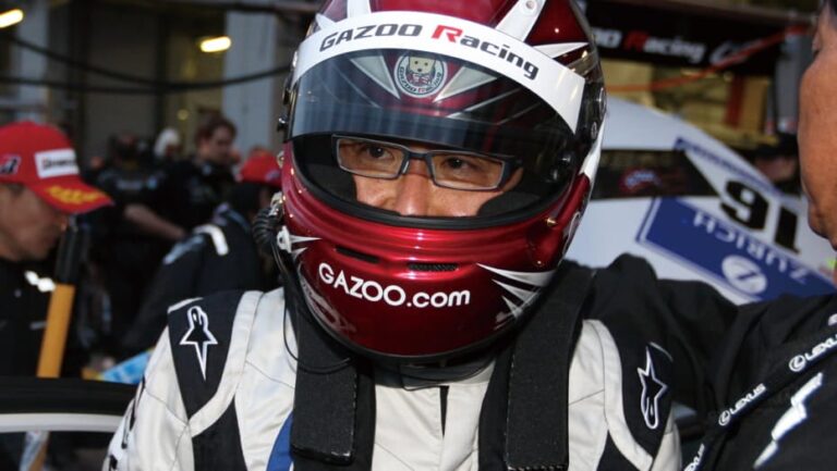 Akio Toyoda, presidente de Toyota, con casco de piloto junto a un automóvil de competición.