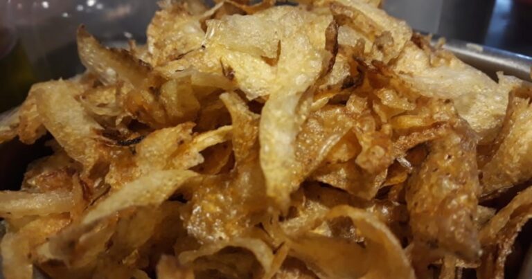 Preparación de fertilizante natural con cáscaras de papa y una botella de vinagre sobre una mesa de jardinería.