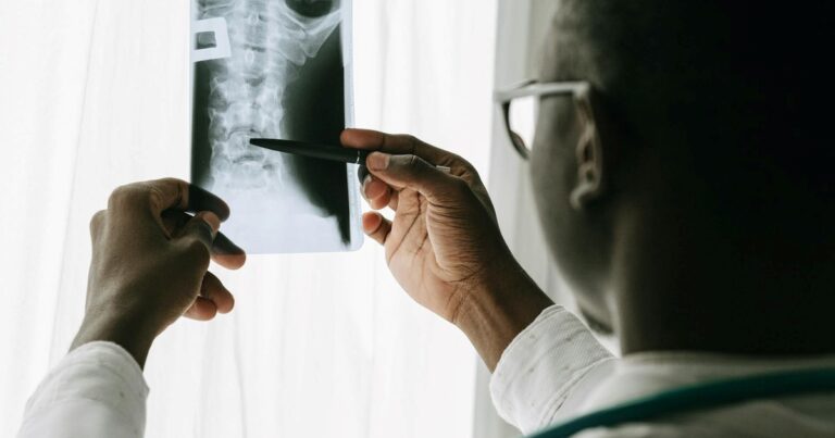 Persona mayor realizando ejercicios de fuerza supervisados por un entrenador en un gimnasio.