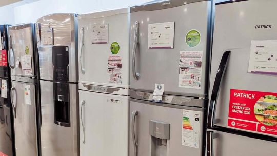 Gráfico de ventas y pilas de electrodomésticos en un depósito, representando la situación del sector.