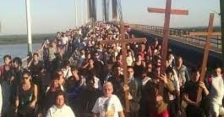 Personas participando en un Vía Crucis nocturno con antorchas en un cerro.