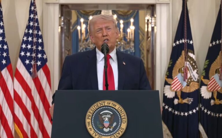 Donald Trump hablando en un evento público, con bandera de EE.UU. de fondo.